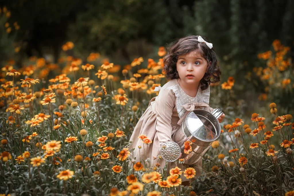 نمونه ژست عکاسی کودک؛ دختر خانم کوچلو در حال آب دادن به گل‌ها